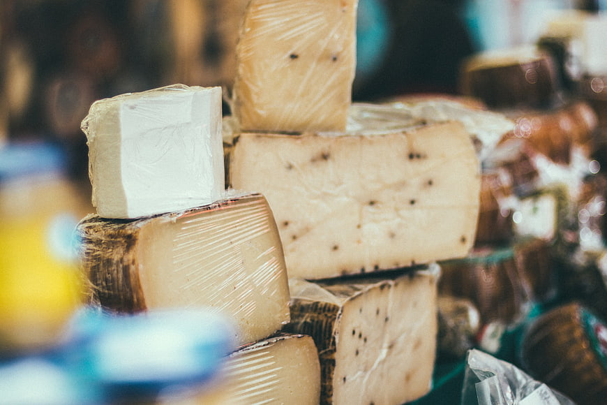 Assorted artisanal cheese blocks wrapped in plastic at market