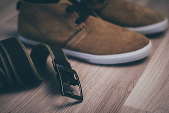 Brown suede shoes and black belt on wooden floor