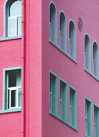 Colorful pink and teal brick building facade with arched windows