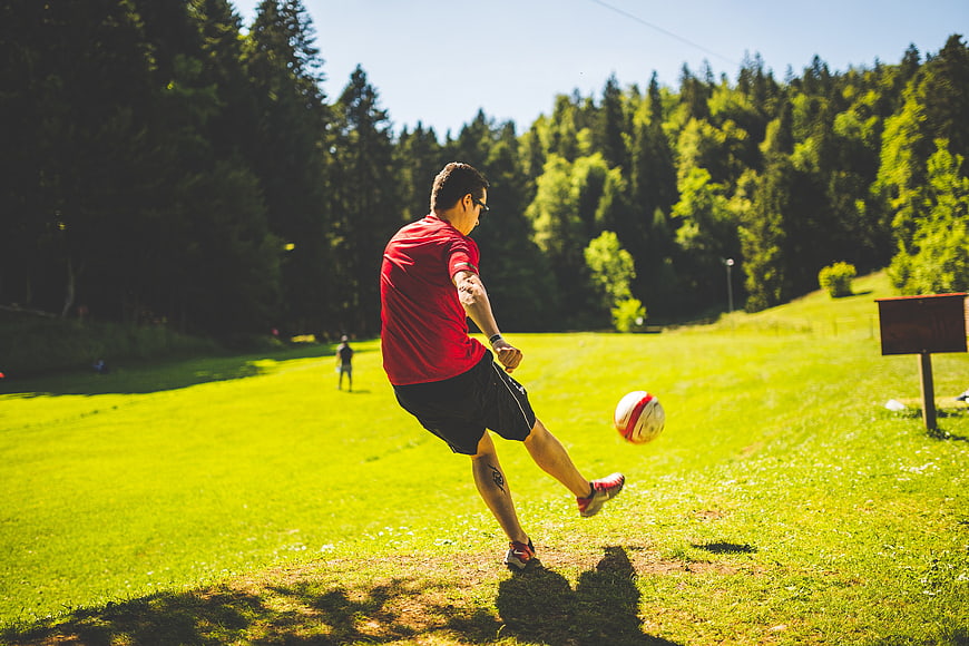 Man Kicking Soccer Ball on Sunny Grass Field