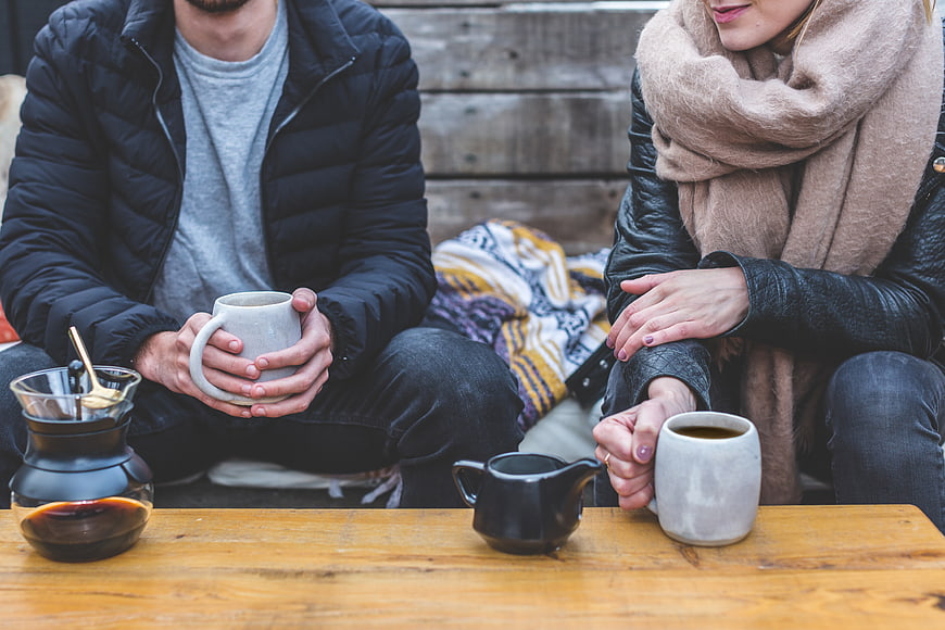 Couple drinking coffee outdoors in winter jackets