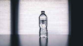 Clear plastic water bottle on table with window light
