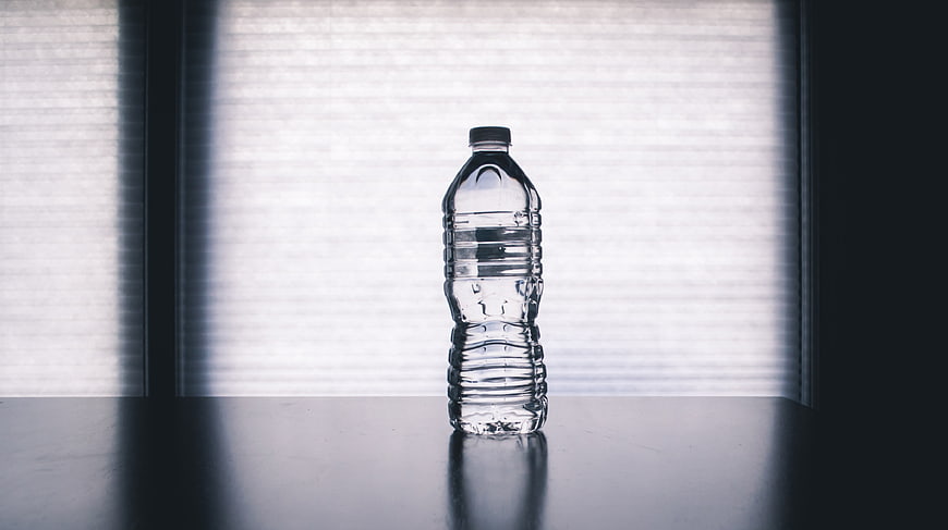 Clear plastic water bottle on table with window light