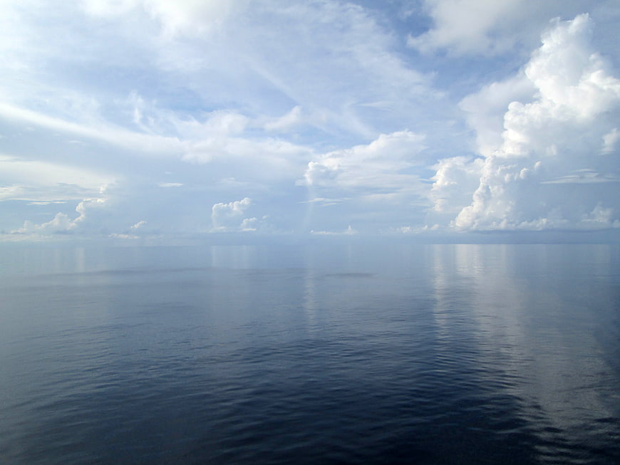 Serene Ocean Horizon with Cloud Reflections and Blue Sky