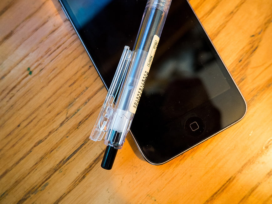Clear pen on black smartphone on wooden table