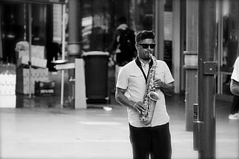 Man playing saxophone on city street in black and white