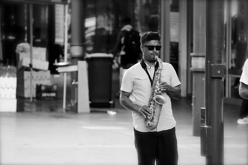 Man playing saxophone on city street in black and white