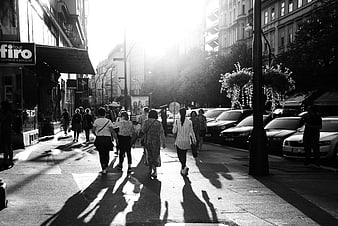 Black and white street photography of pedestrians walking in sunlight