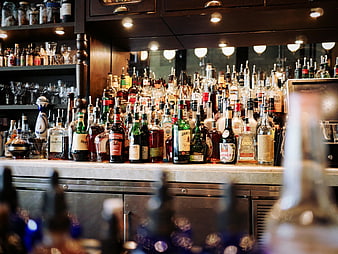 Well-stocked bar counter with liquor bottles and glassware
