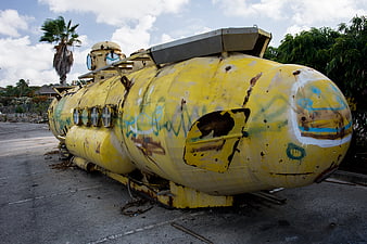 Rusty yellow submarine with graffiti in parking lot
