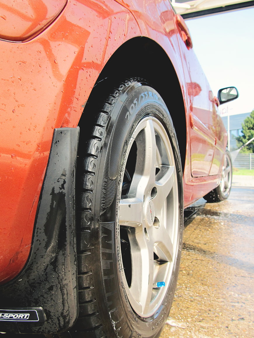 Close-up of wet red car wheel and tire at car wash