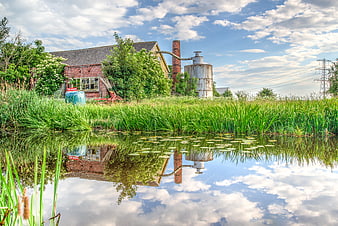 Abandoned brick factory with chimney reflected in pond