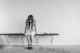 Sad Young Woman Sitting Alone on Bench in Black and White