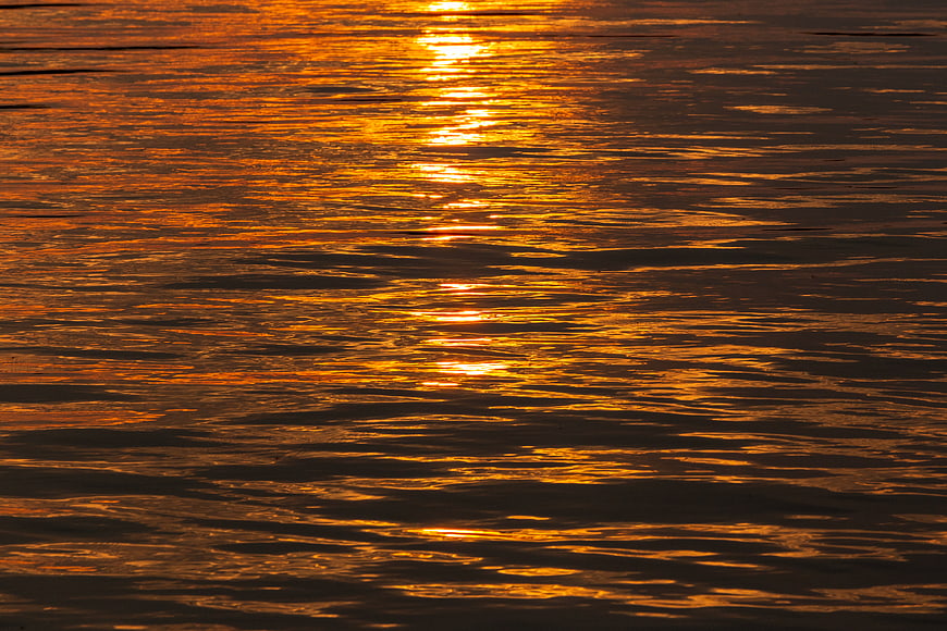 Golden sunset reflection on rippling water surface