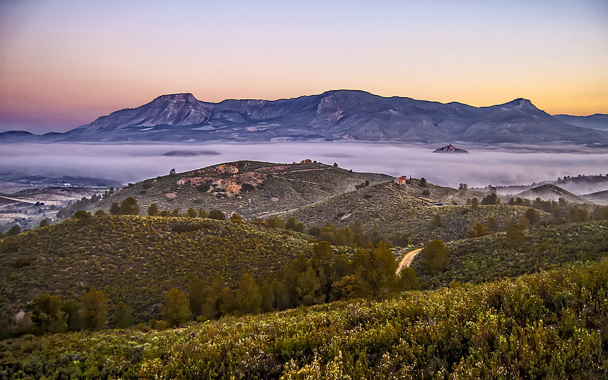 Misty mountain landscape at sunrise with rolling hills and fog