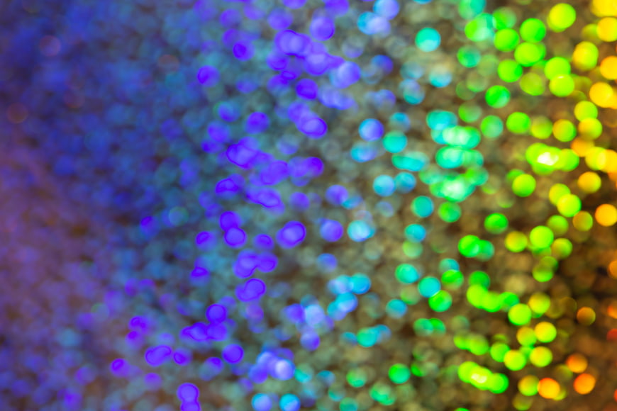 Abstract colorful bokeh lights background with purple and green glow