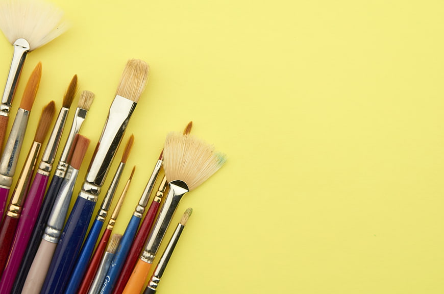 Assorted Paint Brushes on Yellow Background with Copyspace