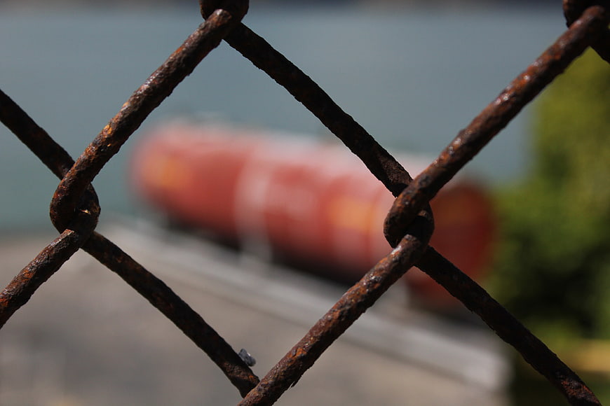 Close-up of rusty chain-link fence with blurred background