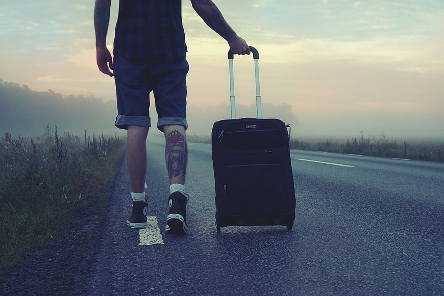 Man Walking on Road with Luggage at Sunset