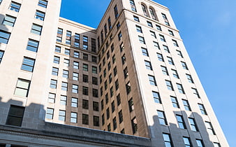 Low angle view of beige office building facade against blue sky