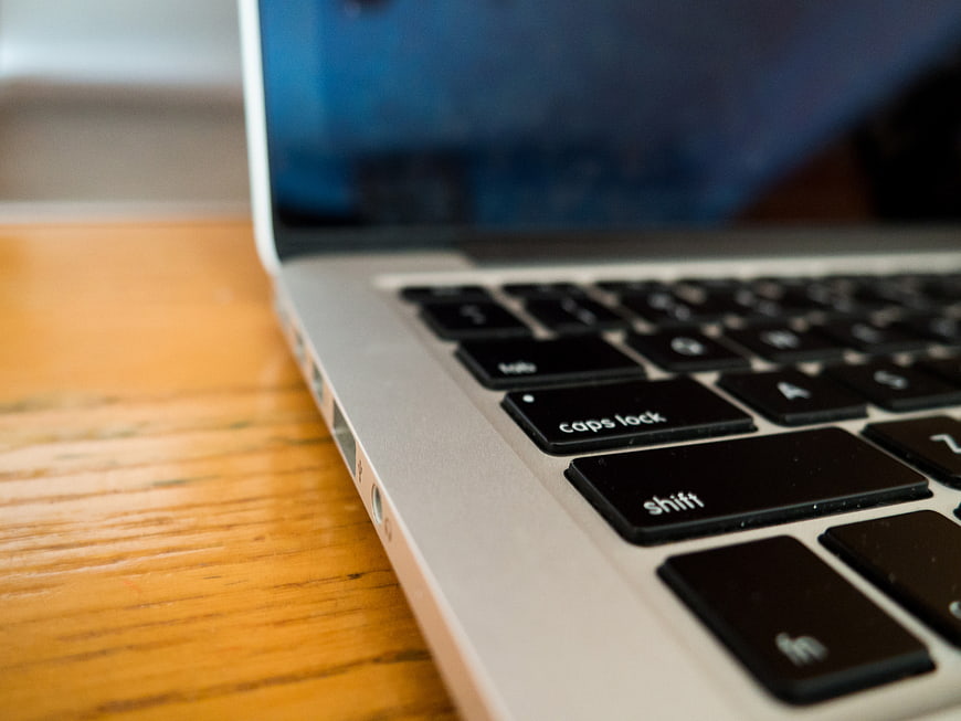 Close-up of silver laptop keyboard on wooden desk