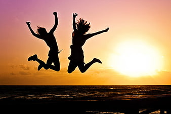 Silhouette of Two People Jumping at Sunset Beach