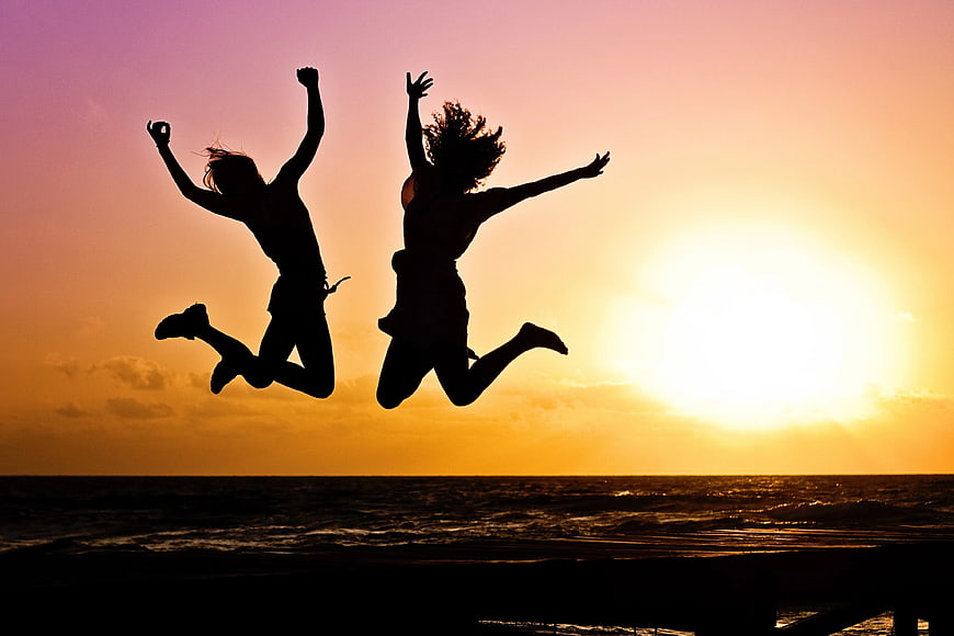 Silhouette of Two People Jumping at Sunset Beach