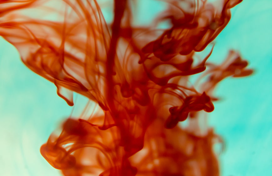 Abstract red ink swirling in turquoise water background