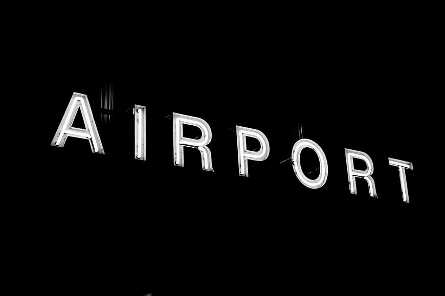 Illuminated Airport Sign Against Black Background