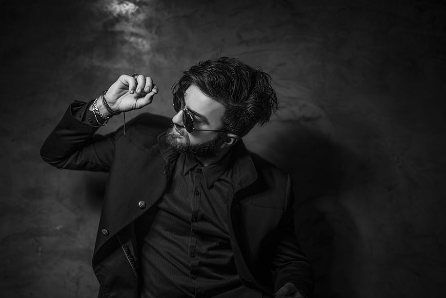 Stylish man in sunglasses and coat, black and white portrait