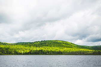 Serene Lake View with Lush Green Hills and Cloudy Sky