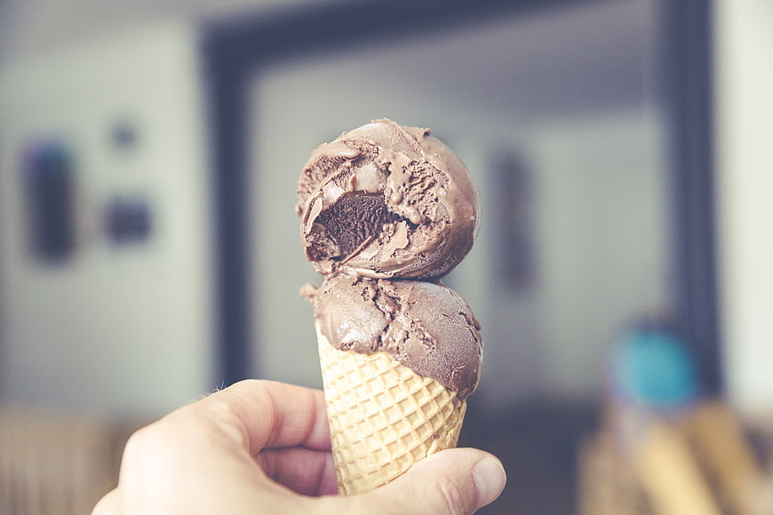Hand holding chocolate ice cream cone with bite taken out