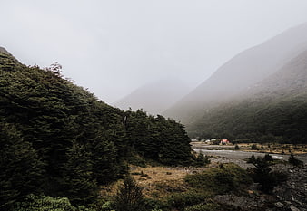 Misty mountain valley with river and distant houses