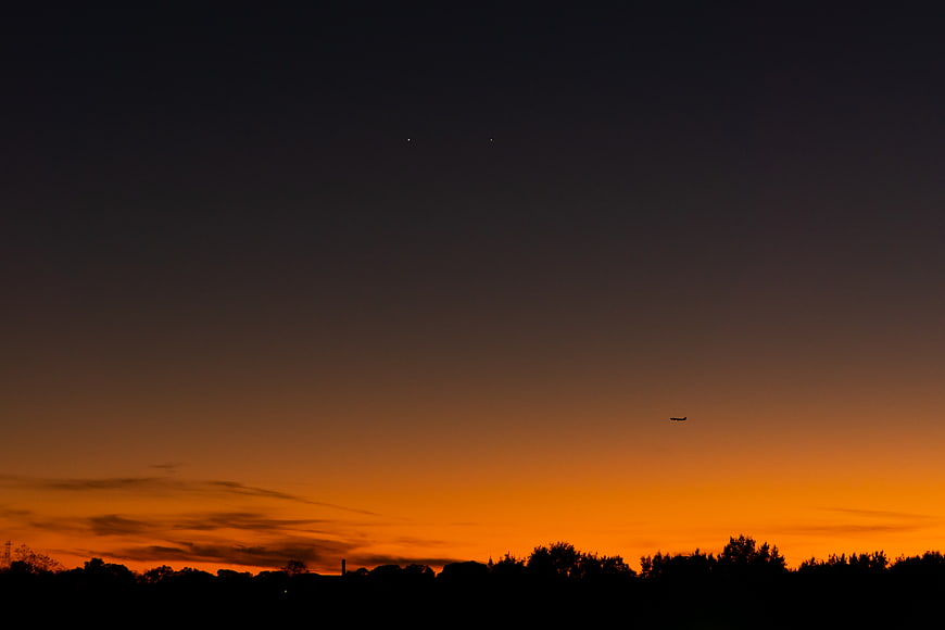 Silhouette of trees against vibrant orange sunset sky