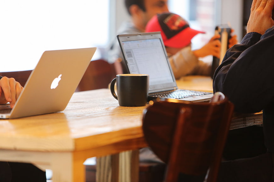 People working on laptops in a cafe with coffee