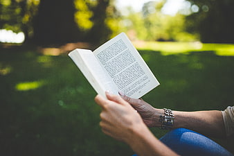 Woman Reading Book in Park with Green Bokeh Background