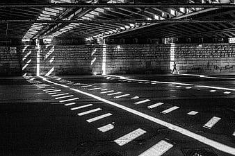 Black and white photo of a runner under a bridge with geometric shadows
