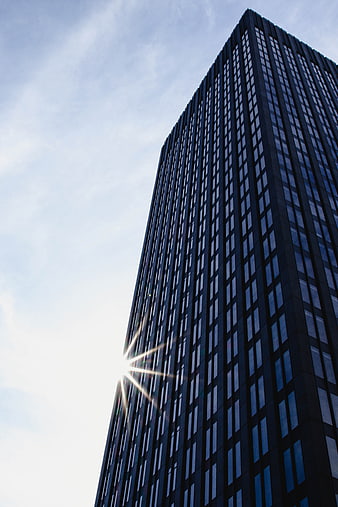 Low angle view of modern skyscraper with sun flare