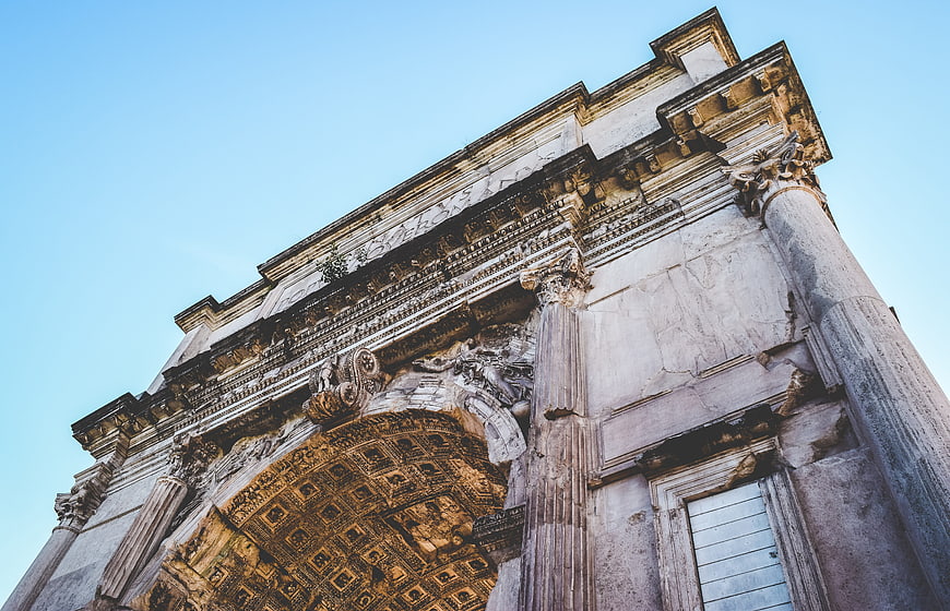 Low angle view of ancient Roman triumphal arch against blue sky