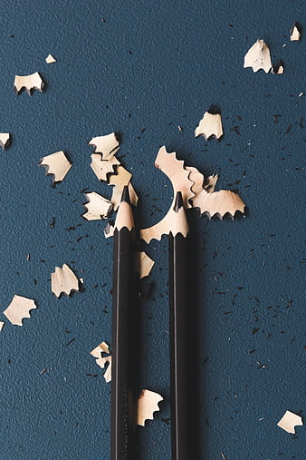 Two Black Pencils with Shavings on Blue Background