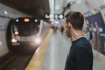 Man with orange earphones waiting for subway train