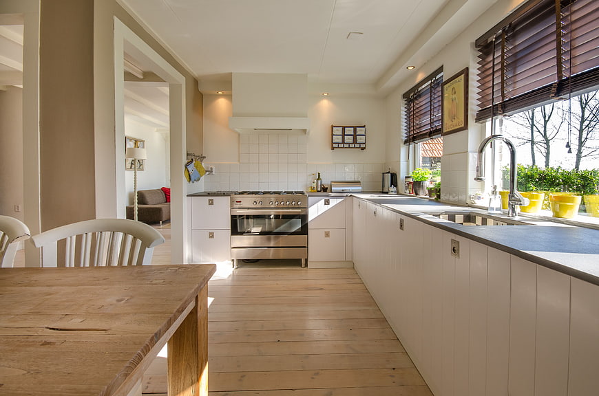 Modern white kitchen with wooden table and natural light