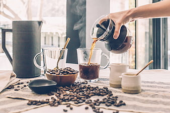 Pouring Fresh Coffee into Glass Mug with Beans