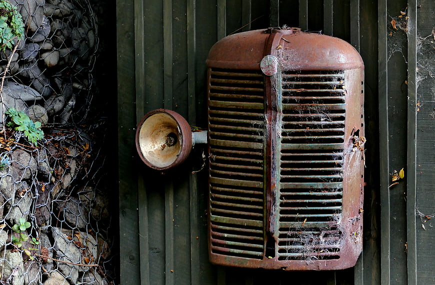 Rusty vintage truck grille and headlight on wooden wall