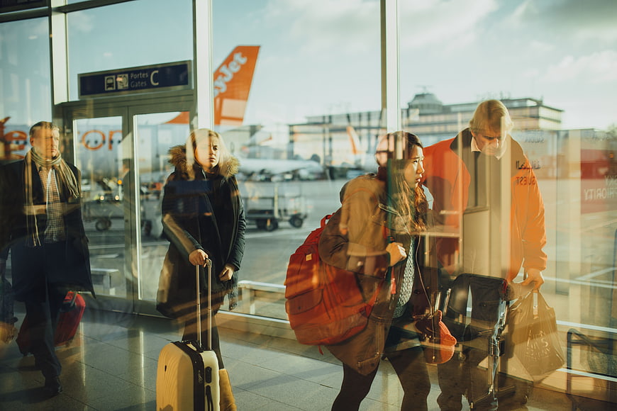 Travelers Walking Through Airport Terminal Glass Doors