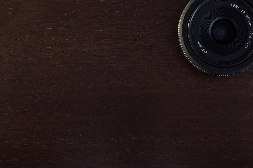 Camera Lens on Dark Wooden Desk Background