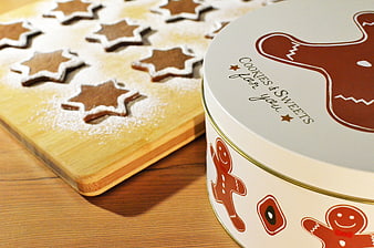 Gingerbread star cookies on wooden board with festive tin