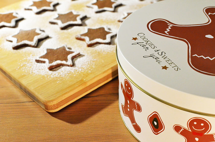 Gingerbread star cookies on wooden board with festive tin