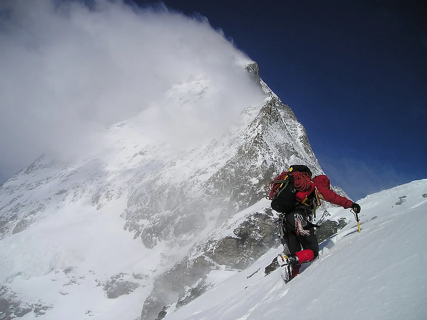 Mountaineer Climbing Snowy Mountain Peak with Backpack