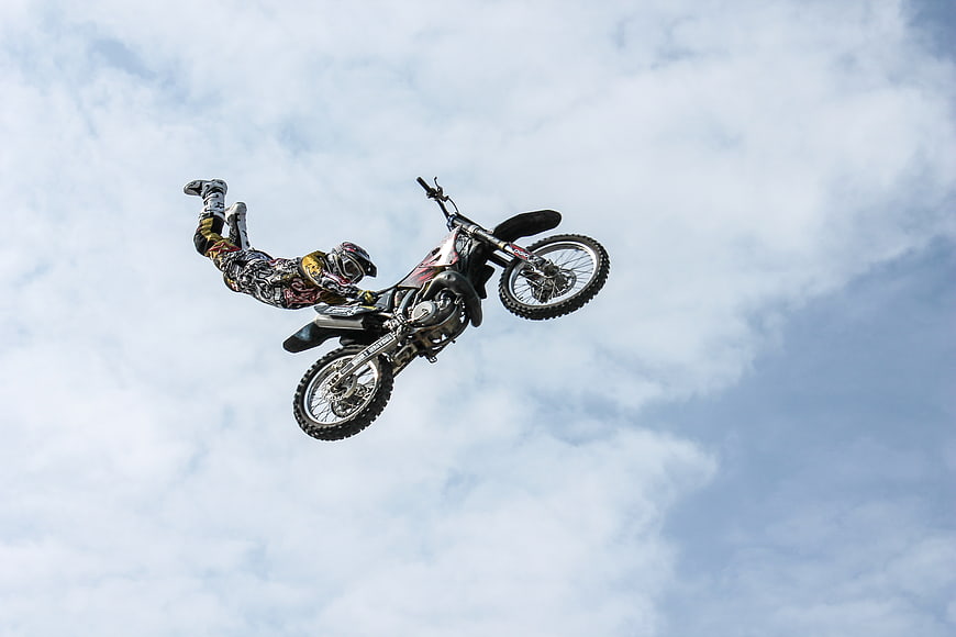 Motocross Rider Performing Mid-Air Stunt Against Cloudy Sky